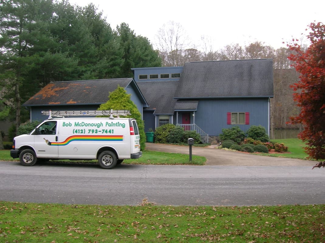 A well painted blue home with the Bob McDonough Painting company van parked in front.