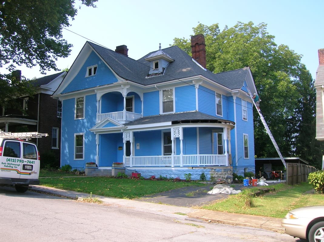 A well painted victorian home with the Bob McDonough Painting company van parked in front.